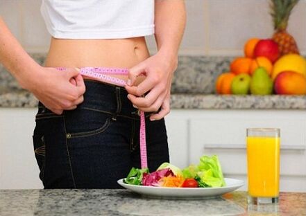 Uma garota que perde peso com uma dieta mede o tamanho da cintura